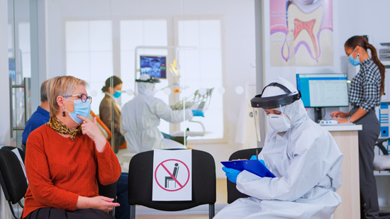 Dentist with face shield talking to patient